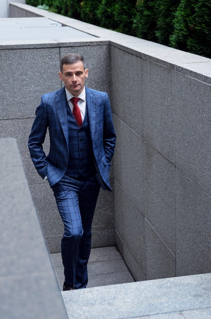 Uomo carismatico in abito scozzese sullo sfondo dell'ufficio del business center Ritratto aziendale di un elegante manager dipendente alla moda Facile da salire le scale