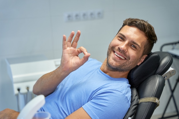 Uomo castana allegro che sorride all'ufficio del dentista