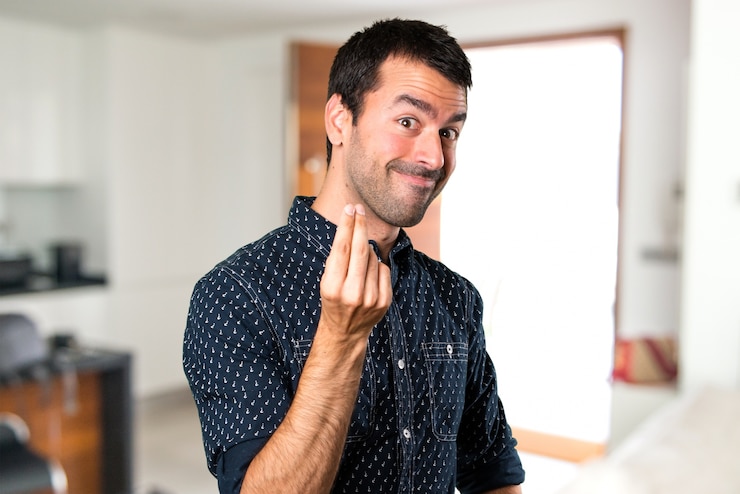 Foto uomo castana che fa gesto dei soldi dentro la casa
