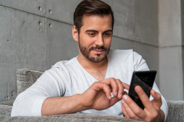 Uomo casual che utilizza smartphone in poltrona