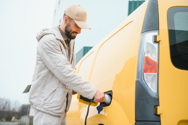 Uomo casual vicino all'auto elettrica in attesa della fine del processo di ricarica della batteria