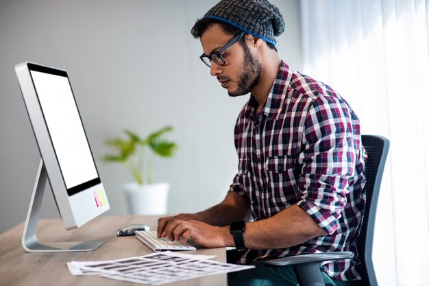 Uomo casuale serio che lavora allo scrittorio del computer