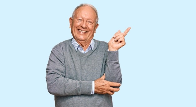 Uomo caucasico anziano che indossa abiti casual sorridendo felice indicando con la mano e il dito di lato