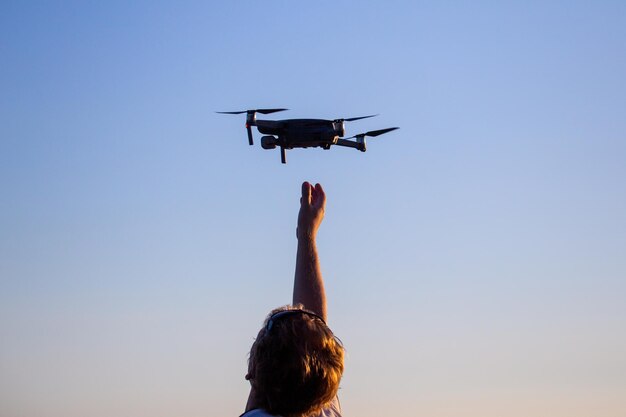 Uomo caucasico biondo che cattura un piccolo drone quadricottero