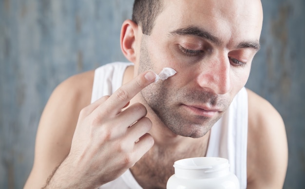 Uomo caucasico che applica crema per il viso.