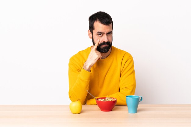 Uomo caucasico che fa colazione in un tavolo che mostra qualcosa.