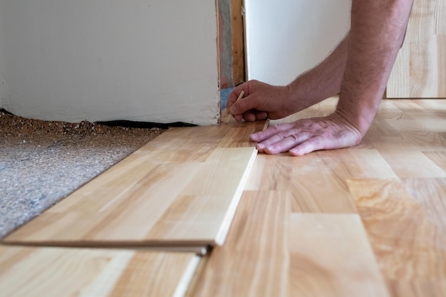 Uomo caucasico che installa il parquet in legno durante i lavori di pavimentazione