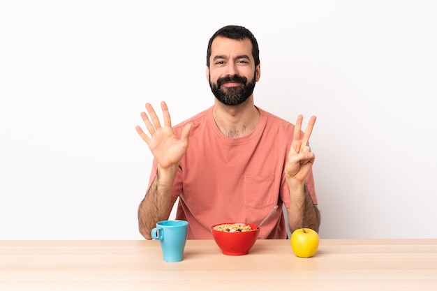 Uomo caucasico che mangia prima colazione in una tabella che conta otto con le dita.