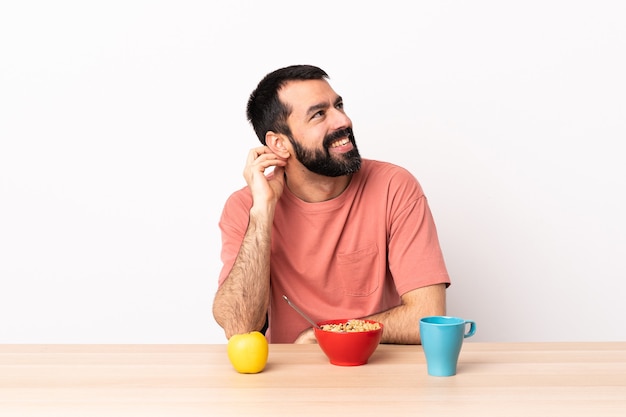 Uomo caucasico che mangia prima colazione in una tabella che pensa un'idea