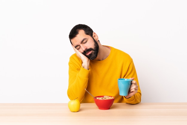 Uomo caucasico che mangia prima colazione in una tavola che fa gesto di sonno nell'espressione dorable.