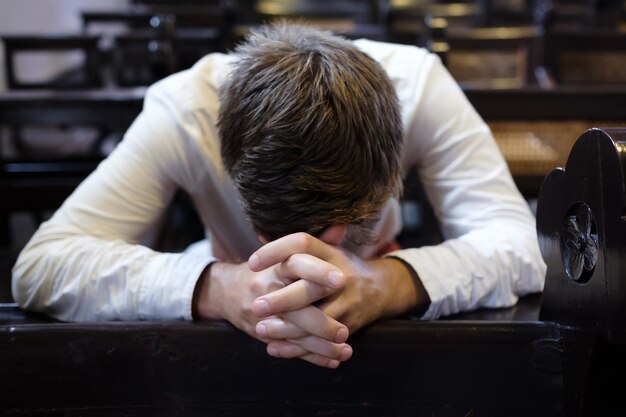 Uomo caucasico che prega in chiesa Ha problemi e chiede aiuto a Dio