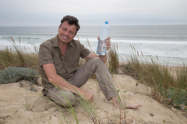 Uomo caucasico che propone alla spiaggia - acqua potabile