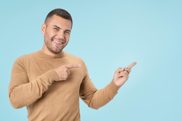 Uomo caucasico che punta con le dita e guardando la fotocamera isolata su sfondo blu