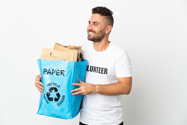 Uomo caucasico che tiene un sacchetto di riciclaggio pieno di carta da riciclare isolato sul lato dall'aspetto bianco
