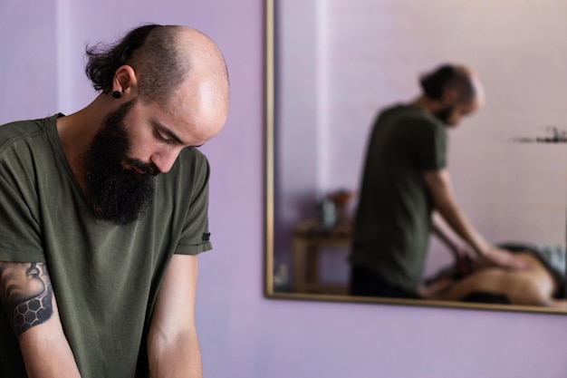 Uomo caucasico con barba che massaggia un paziente irriconoscibile. Copia spazio.