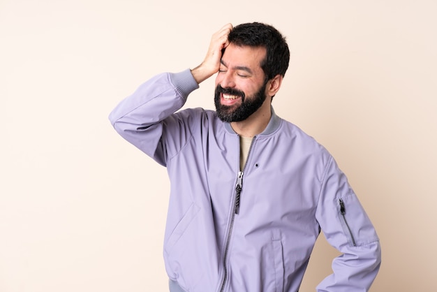 Uomo caucasico con la barba che indossa una giacca sopra isolato sorridente molto