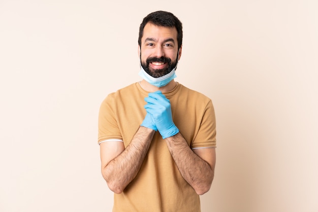 Uomo caucasico con la barba che protegge con una maschera e guanti sopra la risata della parete