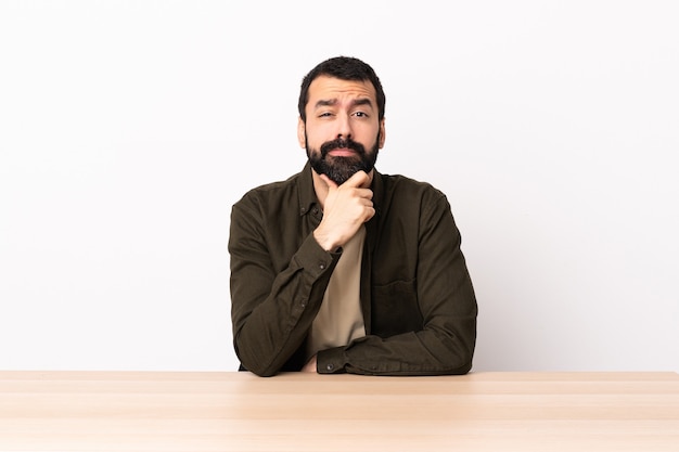 Uomo caucasico con la barba in un pensiero di tabella.