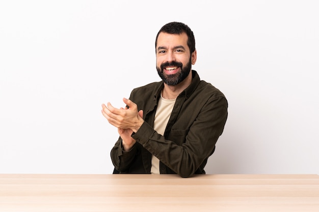 Uomo caucasico con la barba in un tavolo applaudire