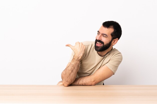 Uomo caucasico con la barba in una tabella che punta di lato per presentare un prodotto.