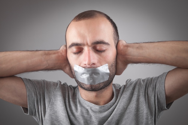 Uomo caucasico con nastro adesivo sulla bocca. Censura