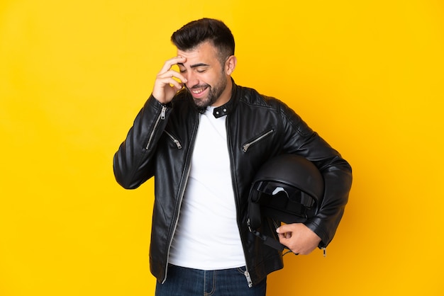 Uomo caucasico con un casco da motociclista sopra la risata gialla isolata della parete