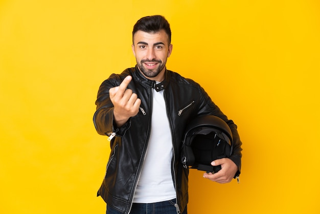 Uomo caucasico con un casco da motociclista su giallo facendo gesto in arrivo