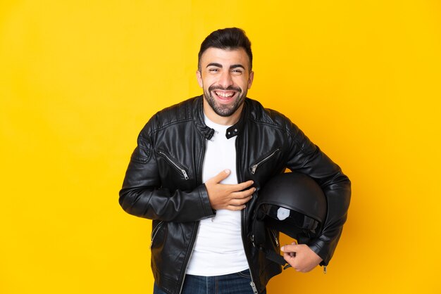 Uomo caucasico con un casco da motociclista su giallo isolato che sorride molto