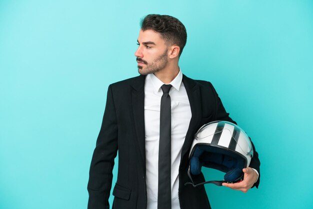 Uomo caucasico d'affari con casco da moto isolato su sfondo blu che guarda al lato