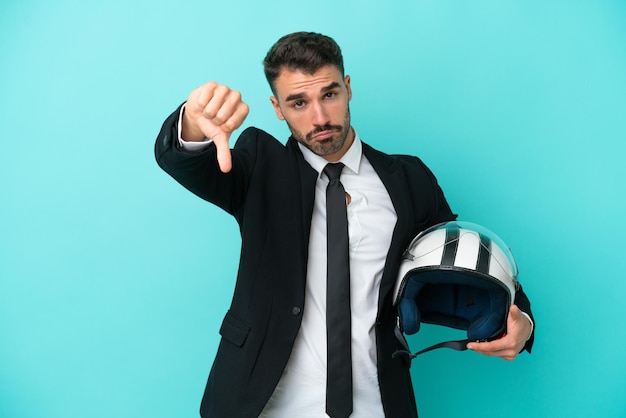 Uomo caucasico d'affari con casco da moto isolato su sfondo blu che mostra il pollice verso il basso con espressione negativa