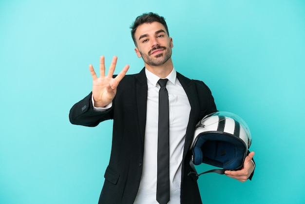 Uomo caucasico d'affari con casco da moto isolato su sfondo blu felice e contando quattro con le dita