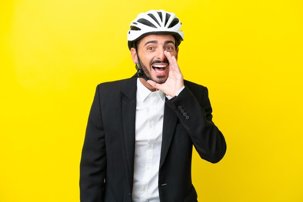 Uomo caucasico d'affari con un casco da bici isolato su sfondo giallo che grida con la bocca spalancata