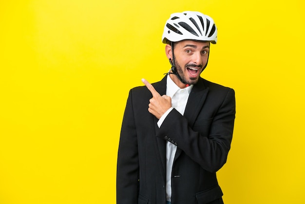 Uomo caucasico d'affari con un casco da bici isolato su sfondo giallo sorpreso e rivolto verso il lato