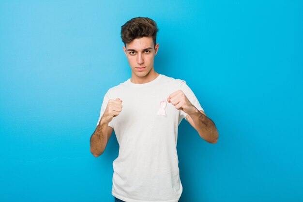 Uomo caucasico dell'adolescente con un arco rosa. Concetto di lotta contro il cancro.