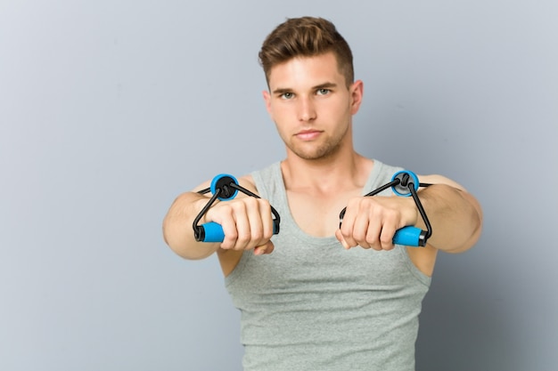 Uomo caucasico di giovane forma fisica che si esercita con un elastico.