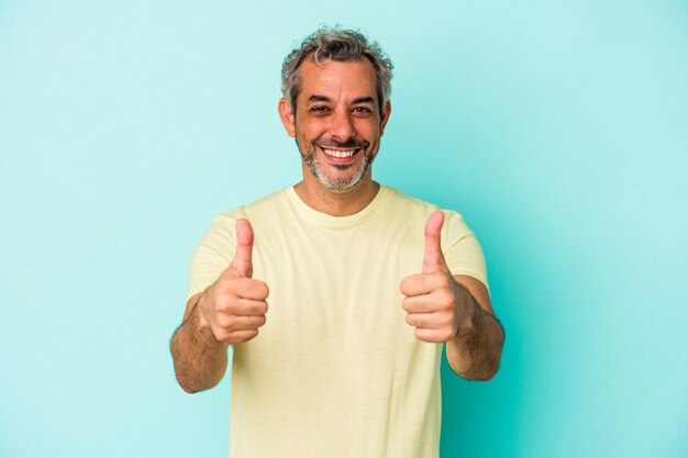 Uomo caucasico di mezza età isolato su sfondo blu sorridente e alzando il pollice
