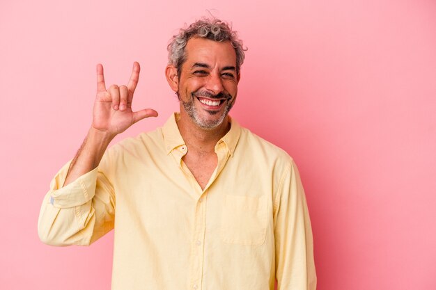 Uomo caucasico di mezza età isolato su sfondo rosa che mostra un gesto di corna come un concetto di rivoluzione.