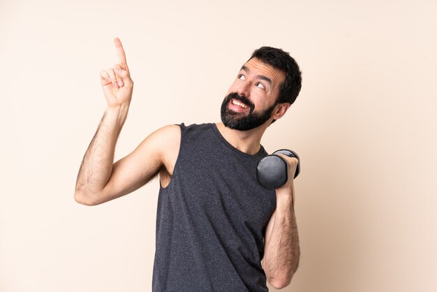 Uomo caucasico di sport con la barba che fa sollevamento pesi indicando su una grande idea