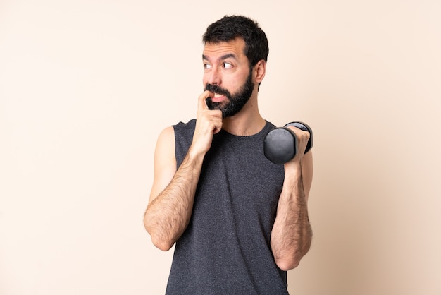 Uomo caucasico di sport con la barba che fa sollevamento pesi isolato