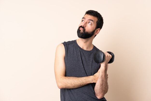 Uomo caucasico di sport con la barba che fa sollevamento pesi sopra isolato