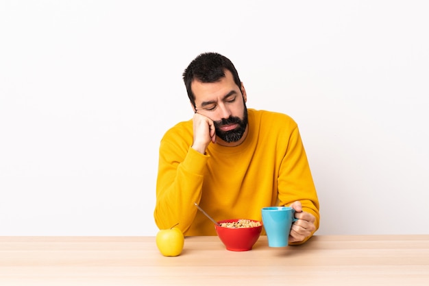 Uomo caucasico facendo colazione in un tavolo con espressione stanca e annoiata