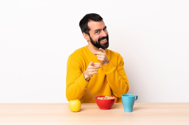 Uomo caucasico facendo colazione in un tavolo sorpreso e indicando la parte anteriore