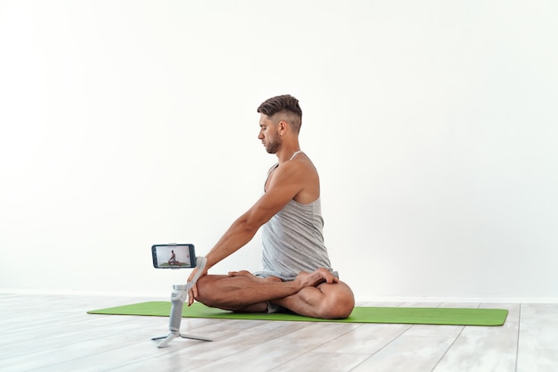 Uomo caucasico in forma che registra un blog o trasmette un allenamento di yoga in streaming