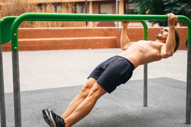 Uomo caucasico senza camicia che fa flessioni calisthenics nel parco all'aperto