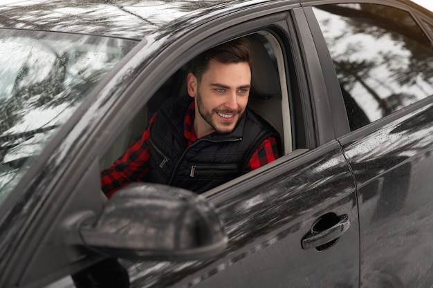 uomo caucasico si siede al volante della sua auto