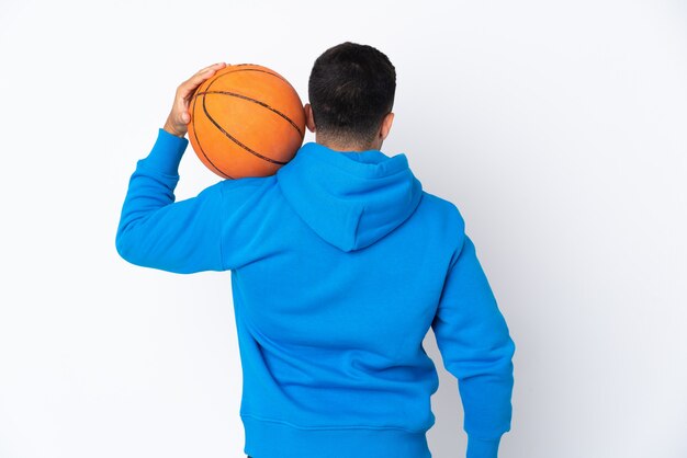 Uomo caucasico sopra la parete bianca isolata che gioca pallacanestro nella posizione posteriore