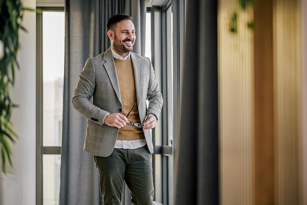 Uomo caucasico sorridente che si toglie gli occhiali dopo il lavoro