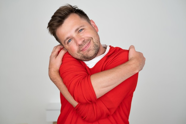 Uomo caucasico sorridente sicuro che tiene abbracciandosi