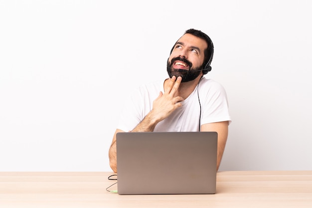 Uomo caucasico telemarketer che lavora con un auricolare e con il computer portatile che osserva in su mentre sorride.