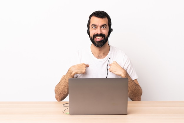 Uomo caucasico telemarketer che lavora con un auricolare e con il laptop con espressione facciale sorpresa.